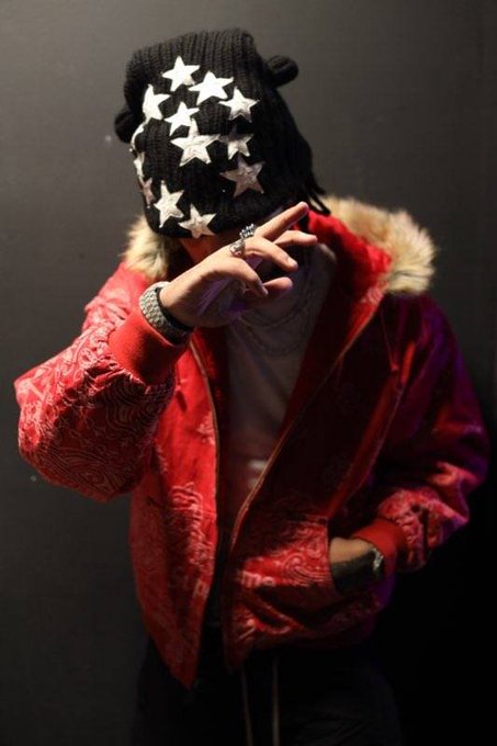 A person wearing a star-covered black ski mask, a red patterned jacket with fur-lined hood, and rings poses with their hand near their face, embodying the "DEADSTAR" persona tied to the launch of the DEADSTAR.XYZ website.