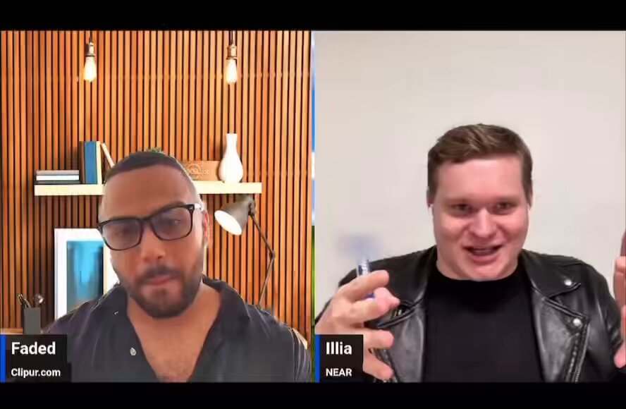 The image shows two men having a conversation over a video call. One man wears glasses and has a beard, while the other man is wearing a leather jacket. The background of the image features wooden panels, suggesting that they are in an office or workspace setting.