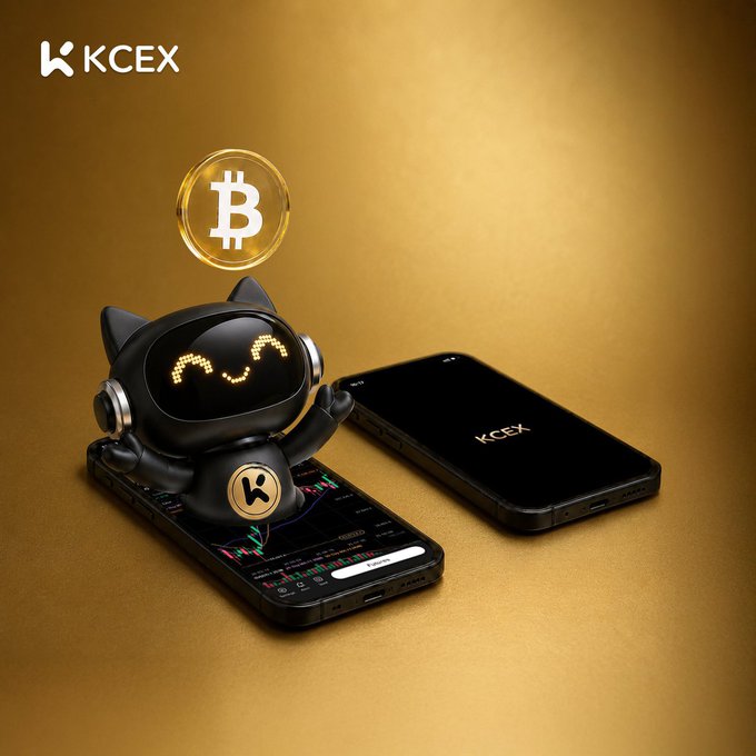 A promotional image for KCEX featuring a cute black cat-like robot figurine sitting on a smartphone displaying a trading chart, with a gold Bitcoin coin floating above it and the KCEX logo in the top left.