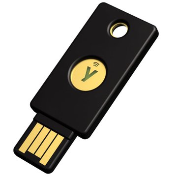 A black YubiKey hardware authentication device featuring a gold checkmark logo is shown, representing physical security key used for cryptographic key management. This relates to the post about securing crypto accounts with YubiKeys that hold different authority levels, where one key handles daily signing and a backup stored safely holds owner permission for account recovery.
