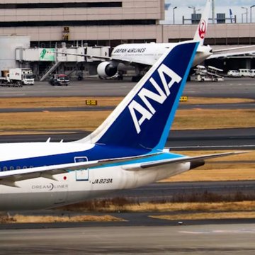 A Japan Airlines (JAL) Dreamliner with registration JA878A and a visible "ANA" tail fin of another aircraft is parked on the tarmac at an airport gate. The post likely references the small mascot visible on the nose, indicating that the popular character $Chiikawa has made a comeback appearance on JAL's livery.