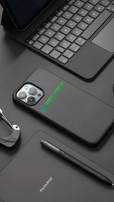 A flat-lay workspace featuring an iPhone with a black "BELDEX" branded case sits alongside a keyboard, stylus, and tablet on a dark desk surface. The Beldex-branded phone case visually reinforces the post's message about Beldex's privacy-focused ecosystem, including BChat and BelNet.
