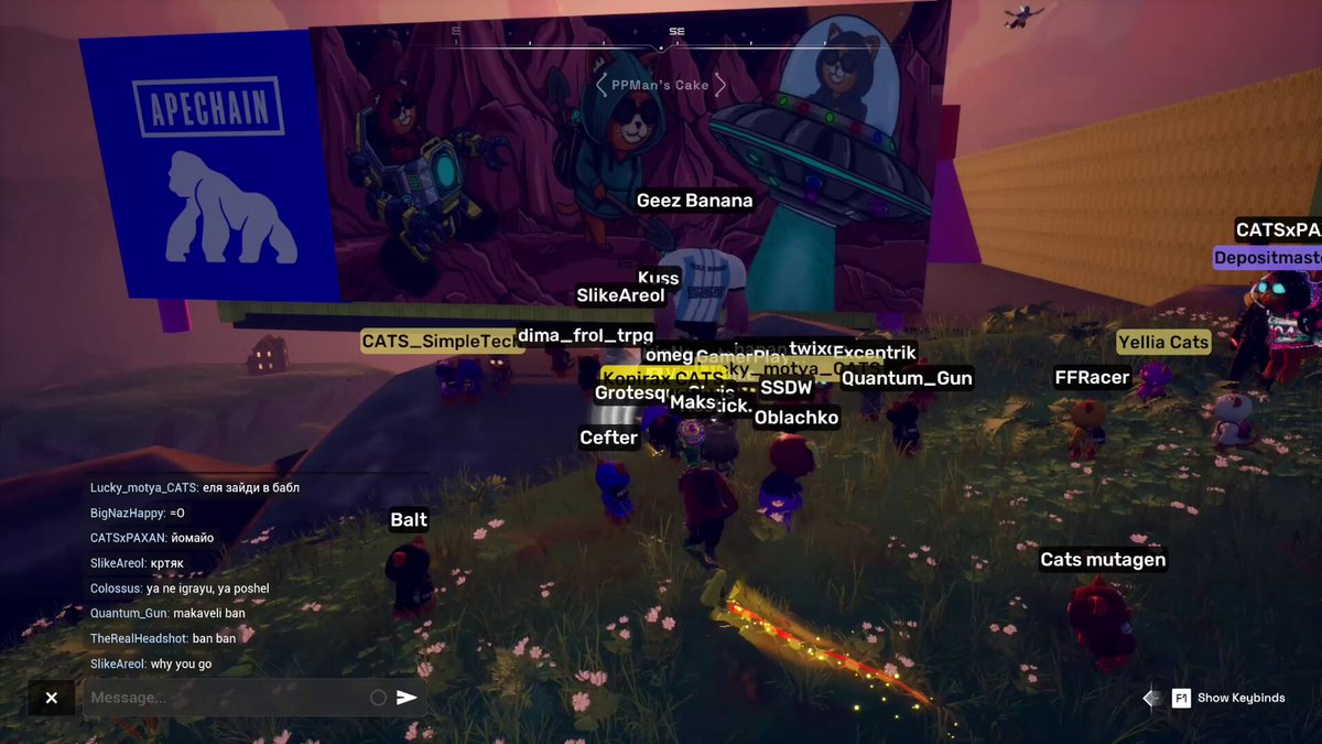 The image shows a group of people playing a video game together, with one player's name displayed as "Kris" and another player's name as "Dee Dee Dee". The players are gathered around a large screen that displays information about their progress in the game. A banner at the top of the screen reads "ApeBrain", indicating that they are playing a game designed by Apegain.
