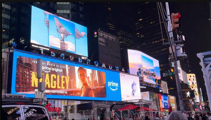 A nighttime view of Times Square in New York featuring illuminated billboards, including an Amazon Prime ad for the show 'Mr. & Mrs. Smith' and an LG logo.