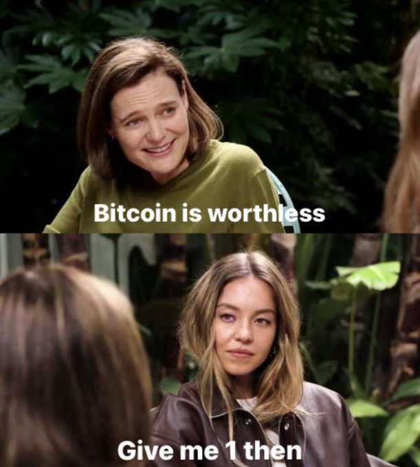 A two-panel meme using an interview scene: the top shows a smiling woman with text 'Bitcoin is worthless' and the bottom shows another woman with text 'Give me 1 then'.