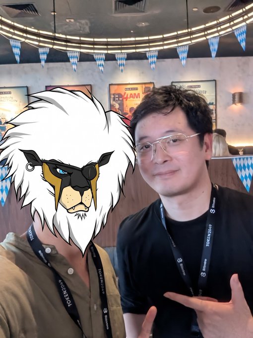 A man poses for a selfie wearing a lanyard that reads "TOKEN2049" and "3" at what appears to be the Token2049 crypto conference, with another person beside him whose face is covered by a cartoon lion sticker. The post ties the image to a moment of gratitude, crediting @Punk9277 and @KaitoAI for helping grow his social media presence and net worth through the "infofi" trend.