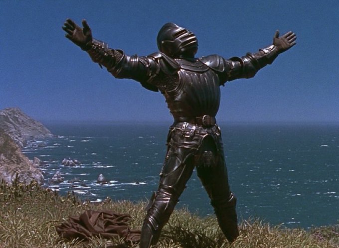 A figure clad in black knight armor stands triumphantly with arms outstretched against a coastal backdrop, mirroring the victorious sentiment of winning "through blood and sweat." The triumphant pose aligns with the post's celebration of victory, though the armor shown resembles the black knight from *Monty Python and the Holy Grail*, a notable cultural reference rather than $KNKnight brand merchandise.