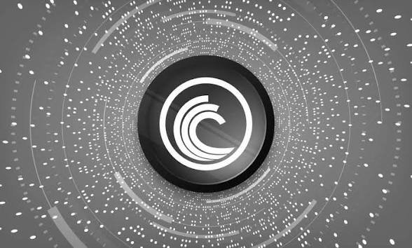 Digital graphic featuring a stylized 'C' logo in the center, surrounded by concentric circles and radiating dots in a gray monochromatic palette, resembling a technological or cryptocurrency motif.