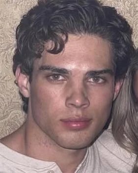 A young man with curly dark hair and a neutral expression looks directly at the camera. The photo humorously accompanies a post suggesting he resembles a typical user of the rainbet platform, playing on tired or unimpressed demeanor.