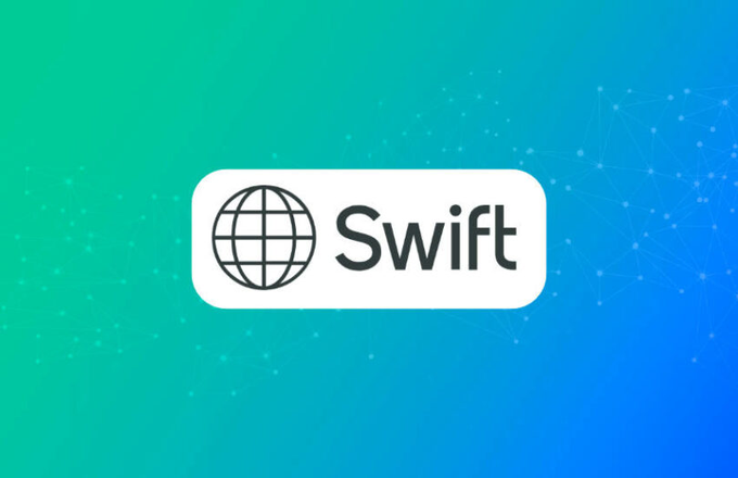 The image features the SWIFT logo displayed on a gradient background, representing the banking network's initiative to test blockchain technology with major banks for faster, 24/7 international money transfers using tokenized deposits.
