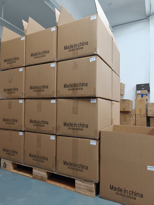 Cardboard boxes stacked on pallets in a warehouse, each labeled 'Made in china 49.6X42.1X35CM'.