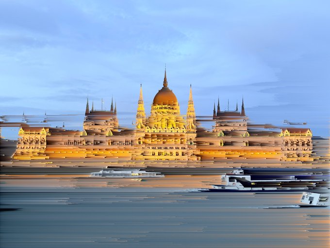 An illuminated, ornate domed building with spires reflecting on a body of water at dusk, captured with a motion blur effect.