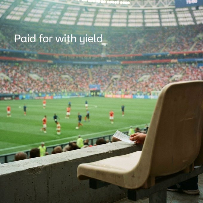 A packed football stadium with players on the pitch, viewed from a stadium seat where a hand holds a ticket, overlaid with the text "Paid for with yield." The image playfully illustrates the post's message about using yield from supplying hemiBTC/VUSD on Vetro and StakeDAO to afford premier experiences like World Cup seats.