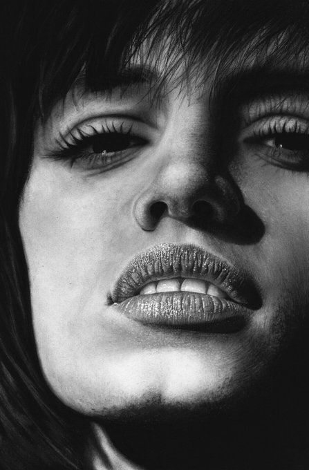 A high-contrast black and white close-up portrait of a woman's face with dramatic lighting emphasizing her eyes and textured lips.