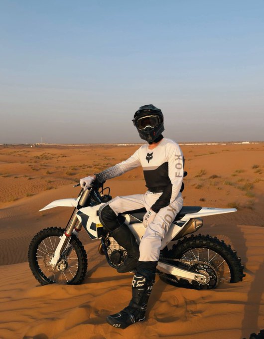 A person in FOX racing gear poses on a dirt bike in the desert, mirroring the "fast and furious" potential of the $BNB meme supercycle. The image features the FOX logo on the rider's apparel.
