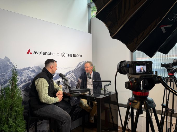 Behind-the-scenes photograph of an interview setup for 'avalanche x THE BLOCK' with two men seated at a table with microphones, filmed by professional cameras on tripods with lighting equipment visible.