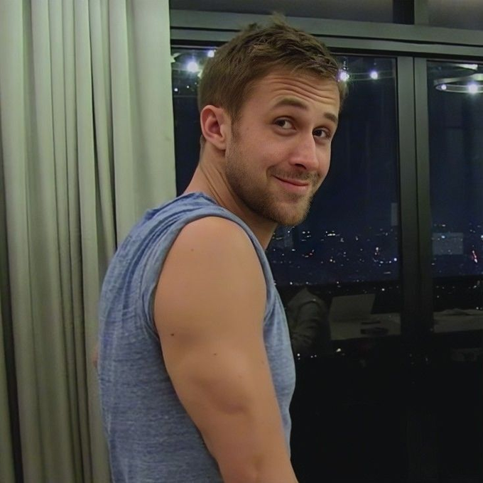 Photo of a smiling man in a blue tank top turning to look at the camera over his shoulder, with a city skyline visible through a window behind him.