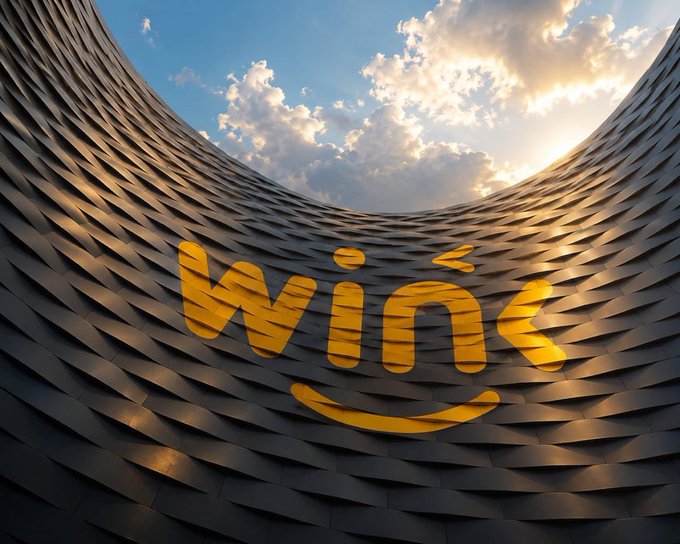 A large yellow 'win' logo with a smile-like swoosh underneath, displayed on the tiled interior of a circular modern building with the sun and clouds visible through the open roof.