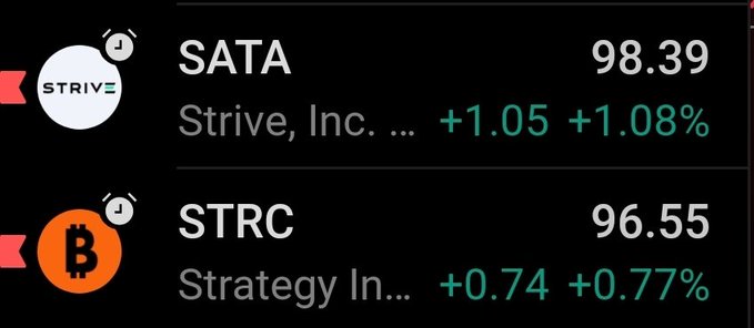 The image shows a black background with two columns of text, each displaying the name of a company along with their current stock prices. One column has "SATA" written in white letters, while the other column displays "STRC" in orange letters. The stock prices are represented by numbers and symbols, indicating that they have been updated or are currently being displayed on the screen.