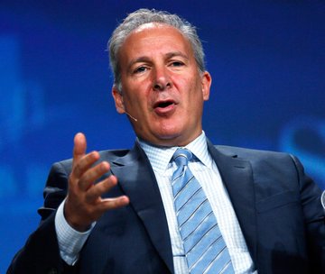 The image shows a man dressed in a suit with a tie, sitting down, and speaking while pointing at something outside of the frame. The background appears to be white, suggesting an event setting or stage. There's also text reading "NEW IN: Investor Peter Schiff says Bitcoin will end the year below $30,000." It seems that this man is presenting his views on Bitcoin and its potential impact on the economy.