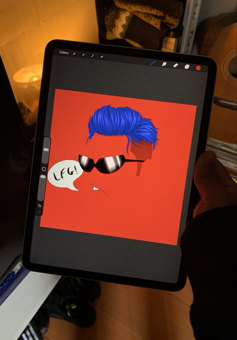 Photo of an iPad displaying a digital drawing of a character with blue hair, shutter shades sunglasses, and a 'LFG!' speech bubble on a red background.