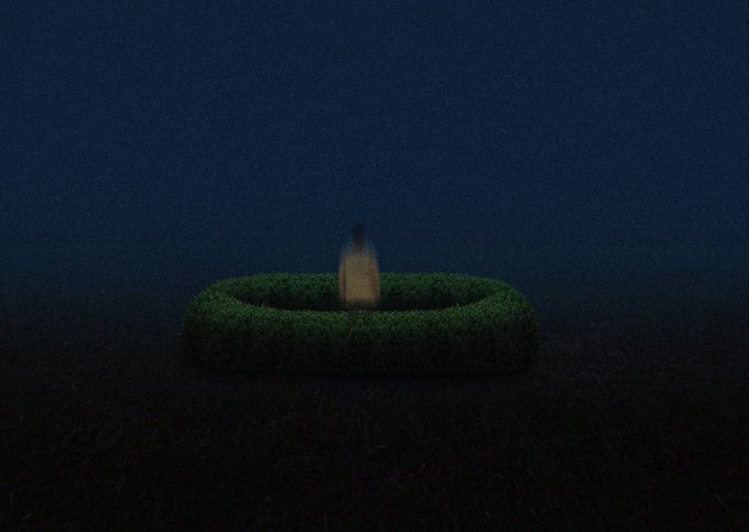 A blurry, low-light photograph showing a small candle glowing inside a circular green hedge or bush against a dark blue, grainy background.