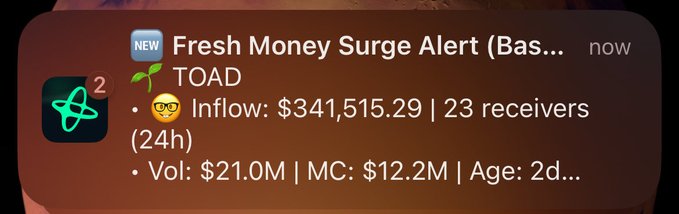 A mobile notification alert showing "Fresh Money Surge Alert" for the ticker $TOAD, displaying a 24-hour inflow of $341,515.29 from 23 receivers, $21.0M volume, $12.2M market cap, and a 2-day age—suggesting sudden capital interest in the token that the post implies may be coordinated by @mdudas.