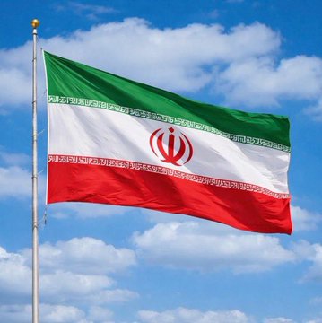 The flag of Iran waves against a backdrop of blue sky and white clouds.