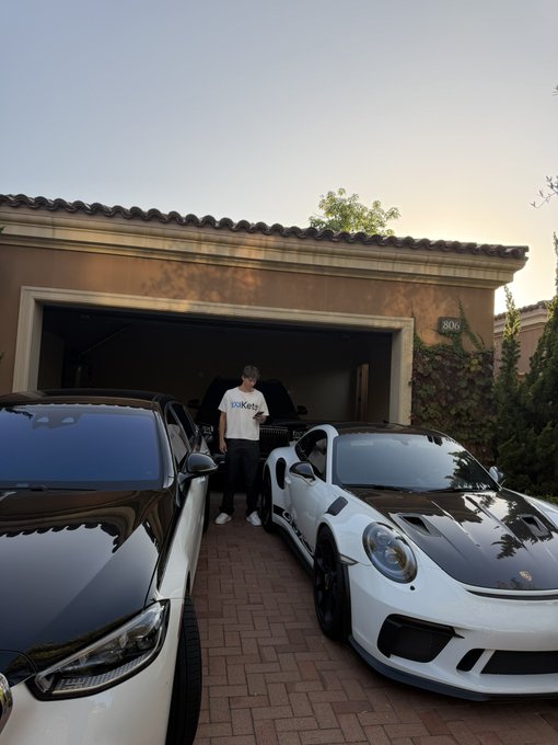 A person stands in a driveway between a black car and a white Porsche 911 Turbo S, with the house number “3806” visible on the wall. The caption “Can sol go back to $200 pls” jokes about SOL’s price falling from a premium level back to around $200, though no SOL ticker or price is visibly shown.