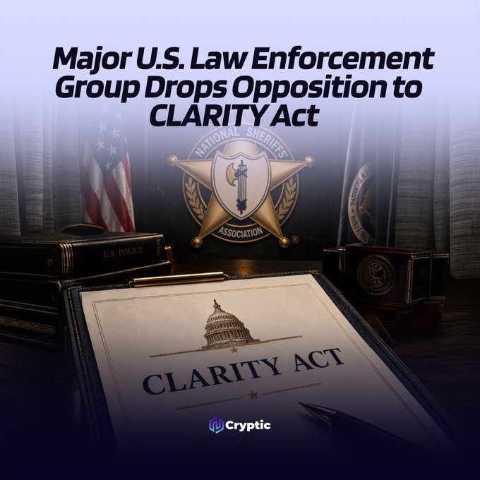 The image displays the headline "Major U.S. Law Enforcement Group Drops Opposition to CLARITY Act" above a composition featuring the National Sheriffs' Association badge, an American flag, and a clipboard labeled "CLARITY ACT" with the U.S. Capitol building illustration. The graphic visually reinforces the news that the National Sheriffs' Association has shifted from opposing the CLARITY Act to a neutral stance, allowing the legislative process to move forward.