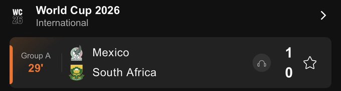 The image shows a scoreboard of the World Cup 2026 between Mexico, South Africa, and Zimbabwe. The score is currently 1-0 in favor of South Africa. The time shown on the scoreboard is 19:00 (7:00 PM).