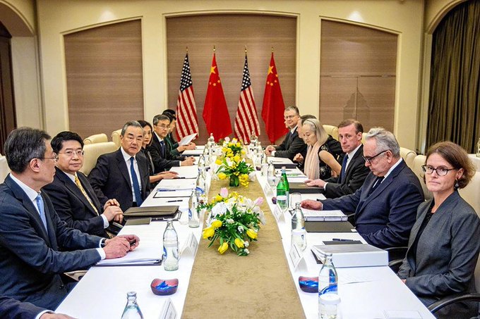 A formal diplomatic meeting between U.S. and Chinese officials, with their national flags displayed behind them at a long conference table, reflects the geopolitical context of the "race" to develop advanced AI systems described in the accompanying text.