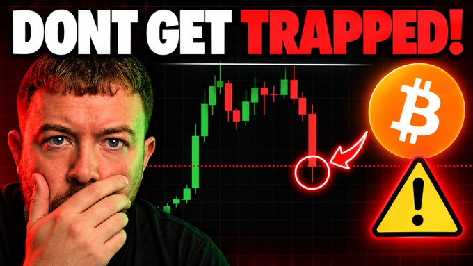 A YouTube thumbnail featuring a man with his hand over his mouth beside a Bitcoin candlestick chart showing a downward trend, with bold text reading "DONT GET TRAPPED!" alongside a Bitcoin logo and warning sign, promoting a video warning viewers about a potential Bitcoin price trap.