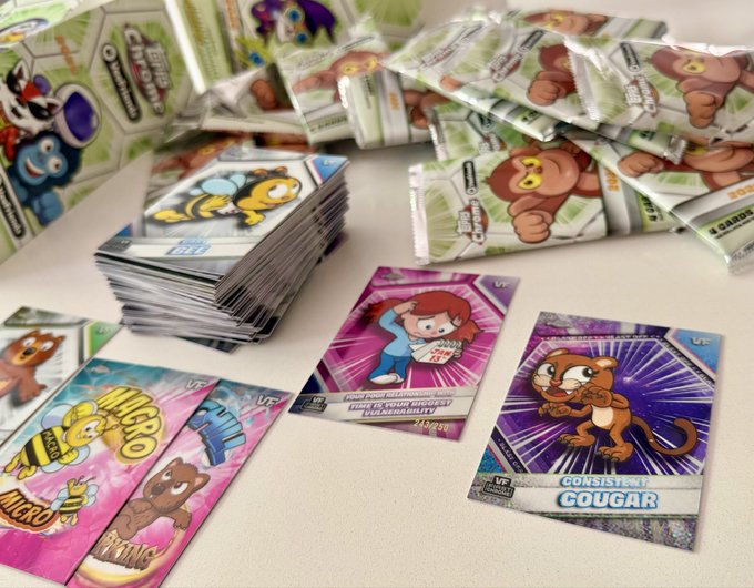 A collection of Veefriends trading cards and booster packs scattered on a table, featuring characters like "Cougar," "Mic Bee," and others, likely sent as a friendly shoutout to EG Jones.