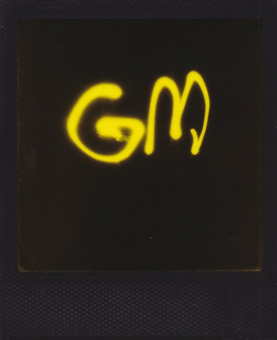 Yellow spray-painted graffiti spelling 'GM' on a dark surface.