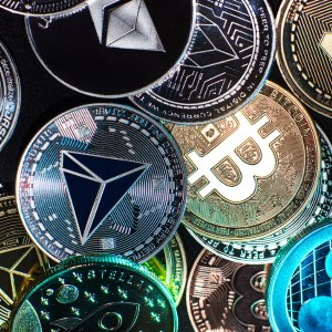 A close-up image showing a collection of physical cryptocurrency coins, including Bitcoin and Ethereum tokens.