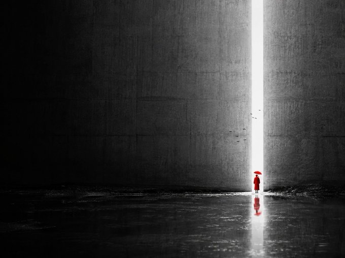 A surreal, minimalist scene showing a figure in a red robe holding an umbrella, standing at the threshold of a massive dark wall where a bright vertical shaft of light opens.