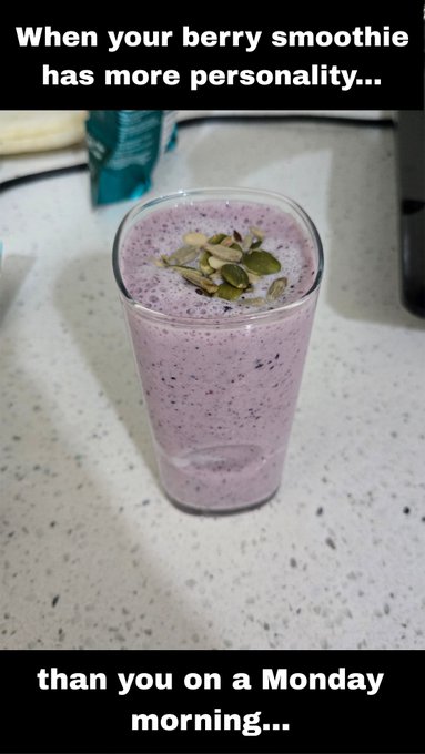 Purple berry smoothie topped with pumpkin seeds in a glass on a countertop, with the caption 'When your berry smoothie has more personality... than you on a Monday morning...'