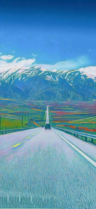 A vibrant, stylized landscape showing a car driving down a straight road toward snow-capped mountains under a bright blue sky, with colorful fields on either side.