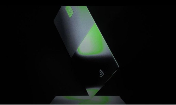 A sleek black contactless payment card with a green chip glows against a dark background, featuring a contactless payment symbol on its surface. The image visually reinforces the post's message by symbolizing how Qubic and Alchemy Pay are simplifying crypto purchases to be as effortless as a simple tap-to-pay transaction available worldwide.