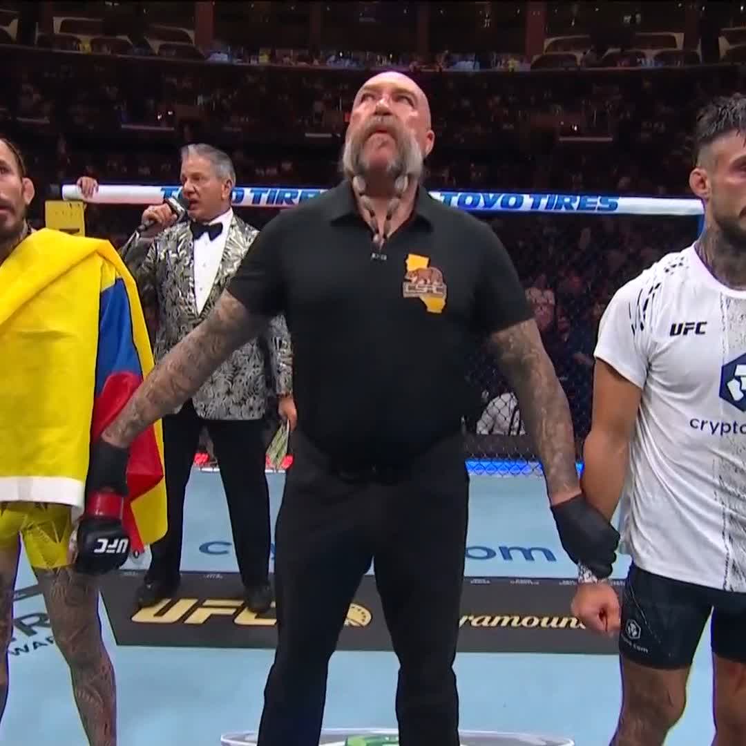 UFC fighter Marlon "Chito" Vera stands in the center of the Octagon wearing a black shirt with California state design, flanked by two opponents and an announcer, with visible "TOYO TIRES" and "UFC" branding on the cage and a "Crypto.com" sponsor logo on the fighter's shorts—capturing his TKO victory referenced in the post.
