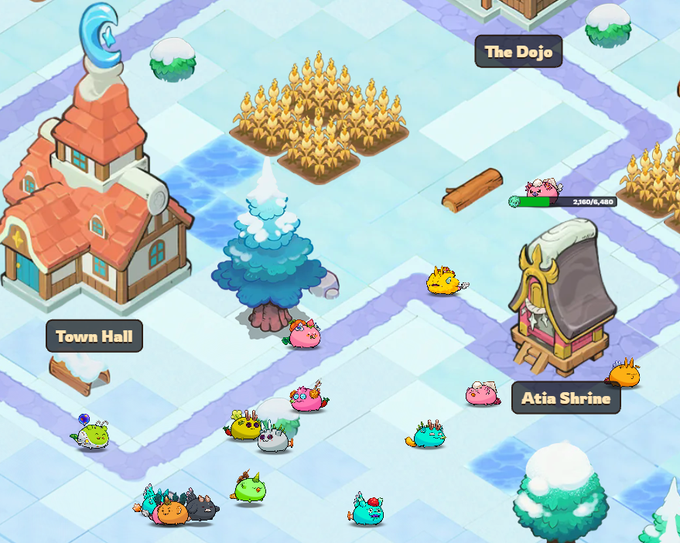 A snowy Axie Infinity map scene showing the Town Hall, Atia Shrine, and The Dojo, with various colorful axie creatures scattered across the icy terrain. The image relates to the post about Axie Terrariums V1.1, which is expected to shift focus back to Axie collectibles, increase demand and trading volume in preparation for bAXS farms.