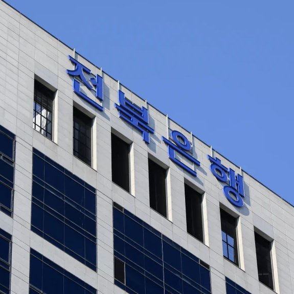 The image shows the upper facade of a modern white building with large blue Korean characters reading "전북은행" (Jeonbuk Bank) against a clear blue sky, visually identifying the institution mentioned in the headline that has partnered with Ripple to replace SWIFT for cross-border transfers.