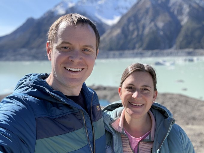 A smiling couple takes a selfie in front of a stunning New Zealand mountain landscape featuring a glacial lake and rocky moraine. The image perfectly captures the post's message about finding clarity and appreciation in nature's cycles, with their joyful expressions mirroring the breathtaking scenery of open skies, fresh air, and majestic peaks.

No text, numbers, or tickers are visible in the image. The "(FOMC)" reference in the post appears to be unrelated to the visual content.