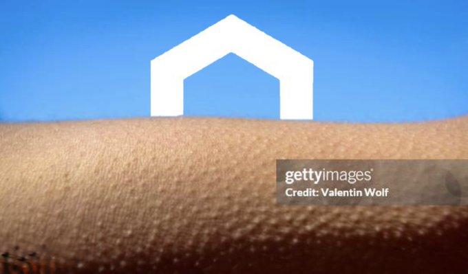 A simple white house icon sits above a textured brown surface against a blue background, with a 'gettyimages' watermark crediting 'Valentin Wolf'.
