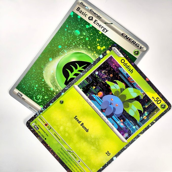 Two custom or artist-made Pokémon cards are shown: a holographic Basic Grass Energy card (SVE 001) and an Oddish card featuring a unique cityscape art design.