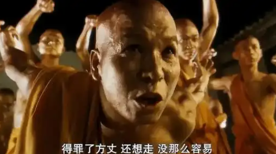 A scene from a martial arts film showing a bald monk in the foreground with other monks behind him, featuring Chinese subtitles.