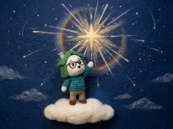 A small felted figurine of a person in a green hat and glasses stands on a wool cloud, reaching toward a glowing star and rainbow in a painted night sky.