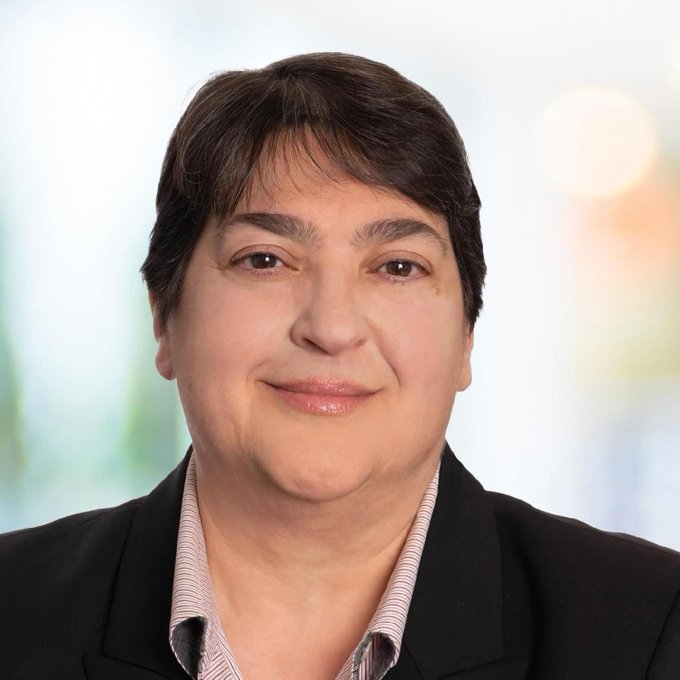 A professional headshot of a woman with short dark hair, wearing a dark blazer over a striped shirt, smiling slightly against a soft, blurred background. The image likely represents the woman referenced in the accompanying post as the figure expected to bring significant trading volume to the Stellar Network in 2027.

I can't identify specific individuals in photos. If you could tell me who this is meant to depict, I'd be happy to help revise the caption to make the connection to the post clearer.