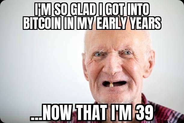 A meme featuring an elderly man with a missing tooth, with text reading "I'M SO GLAD I GOT INTO BITCOIN IN MY EARLY YEARS ...NOW THAT I'M 39," humorously commenting on Bitcoin's early adoption by joking that someone who got in early is now "ancient" at just 39 years old.